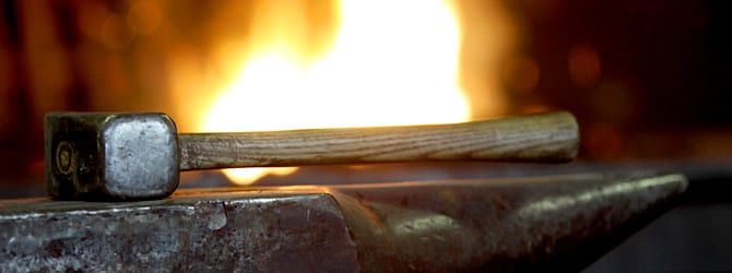 Hammer und glühendes Eisen im Schmiedefeuer
